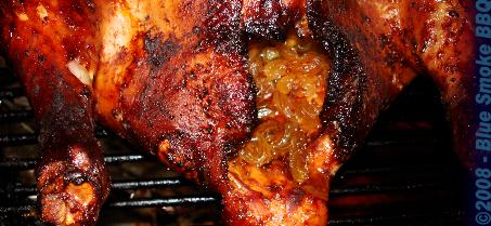 Foto van met gele rozijnen gevulde kip op de barbecue door Blue Smoke BBQ.