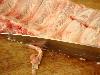 Foto van het afsnijden van los hangende stukjes vlees en vet van de rib slab.